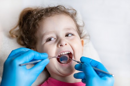 Smiling young girl during a gentle dental check-up with a pediatric dentist